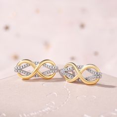 A beautiful way to tell her you'll love her for eternity, these stunning earrings offer that sentiment in shimmering style. Created in two-toned sterling silver, this design pairs polished yellow gold and stone-lined white gold ribbons together in an elegant looping infinity pattern. Celebrate your everlasting love with these darling fashion earrings.Carat Weight: 0.6 ctStone Size: 1 mmStone Type: Jeulia® StoneNumber of Stones: 60 Stone Shape: RoundStone Color: Diamond WhiteWeight: 3.97 gWidth: Elegant Gold Infinity Earrings, Gold Infinity Earrings For Anniversary, Elegant Infinity Earrings For Anniversary, Gold Infinity Earrings For Formal Occasions, Elegant Infinity White Gold Earrings, Elegant White Gold Infinity Earrings, Infinity Pattern, Silver Earrings Online, Infinity Love