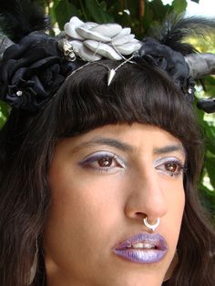 a close up of a person with makeup and flowers in her hair wearing a head piece