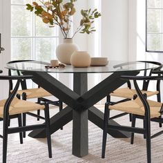 a dining room table with white chairs and a vase filled with flowers on top of it