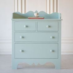 a blue dresser with two drawers and a cup on top