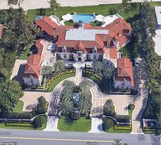 an aerial view of a large mansion surrounded by palm trees