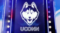 the uconn logo is displayed on an illuminated screen in front of bright lights