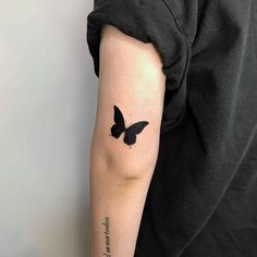 a person with a black butterfly tattoo on their arm and the words, love is in the air