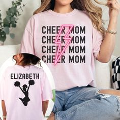 Show your support for your cheerleader with our custom Cheer Mom Comfort Colors Shirt. This personalized cheer comp shirt is the perfect gift for any cheer mom, featuring a unique design that celebrates the cheer mom life in style. Made with high-quality materials, this cheerleader team mom apparel is comfortable to wear during those intense cheer competitions. Whether you're cheering from the stands or running errands, our custom cheer mom tee will keep you cozy and stylish through your cheer m Customizable Pink Tops For Game Day, Pink Team Name Tops For Team Events, Pink Tops With Team Name For Team Events, Customizable Short Sleeve Tops For Team Events, Pink Team Spirit Tops With Team Name, Pink Tops With Team Name For Team Spirit, School Spirit Tops For Cheerleading Sports Season, School Spirit Tops For Cheerleading During Sports Season, Team-colored Tops With Graphic Print For Cheerleading