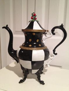 a black and white striped tea pot with gold trimmings sits on a table