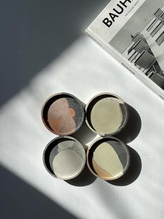 four small bowls sitting on top of a table next to a magazine and some scissors