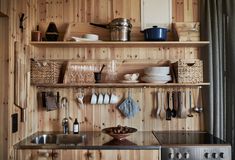 a kitchen with wooden walls and shelves filled with utensils