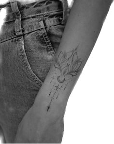 a woman's arm with a cross and flower tattoo on it