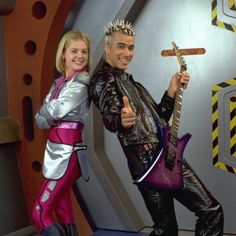 the man and woman are posing for a photo in front of a wall with an electric guitar