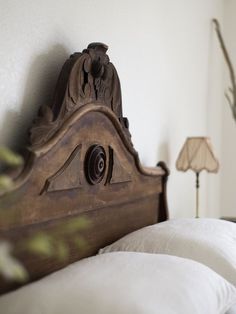 a bed with white pillows and a wooden headboard on it's side next to a lamp