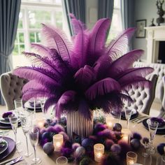 a centerpiece with purple feathers and candles is displayed on a table in front of a window