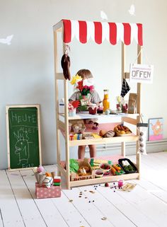 a small child is standing in front of a doll house with food on the floor