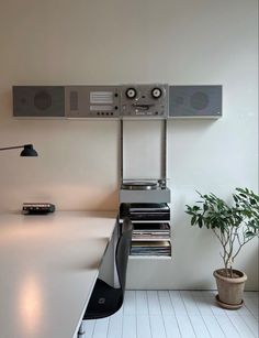 an audio system is mounted on the wall next to a potted plant and bookshelf