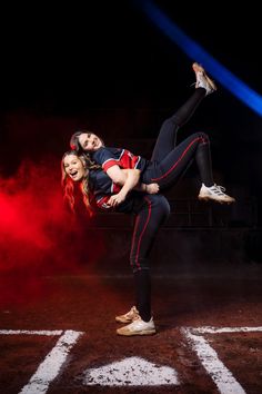 two young women are dancing on the baseball field