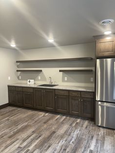 an empty kitchen with stainless steel appliances and wood flooring, is shown in this image