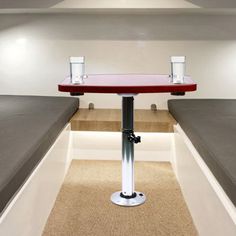 a red table with two glasses on it in the middle of a room filled with benches