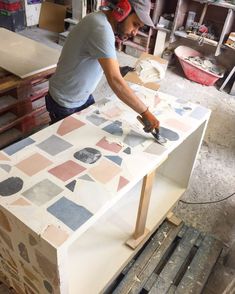 a man working on a piece of art in a shop with tools and materials around him