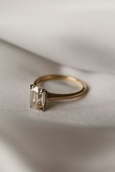 an engagement ring with a single stone in the center on a white cloth background, close up