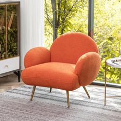 an orange chair sitting on top of a rug in front of a glass door and window