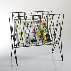 a magazine rack with magazines in it sitting on a table next to a white wall