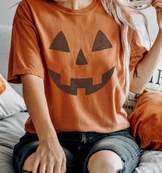 Retro Pumpkin Face Tee Shirt, Vintage Funny Jack O Lantern Halloween Tshirt The Comfort Colors C1717 100% Ring Spun Cotton T-Shirt is very appropriately-named. All colors are inspired by nature and have a perfect lived-in, weathered look. Shirts are sent through a unique dyeing process that makes them incredibly soft and long-lasting. Each piece is soft-washed 50 times before making its way to you! Stitched at the collar, armhole, sleeves and bottom hem for ultimate durability, you will notice the density and quality of this shirt, but won't mind living in it. COMFORT COLORS 1717 ADULT TEE 6.1 Oz/SqYd 100% Ring Spun Cotton Soft-washed garment-dyed fabric Double-needle collar Twill taped neck and shoulders Twill label Relaxed fit Double needle armhole, sleeve and bottom hems Tubular body PR Pumpkin Face Tshirt, Cotton Halloween Shirt, Spooky Orange T-shirt For Fall, Brown Screen Print Top For Fall, Orange Graphic Print T-shirt For Fall, Brown Graphic Print T-shirt For Fall, Spooky Orange Crew Neck Top, Casual Orange Tops For Halloween, Orange Cotton Tops For Halloween