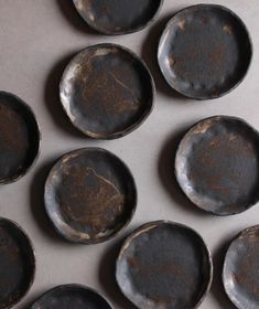 nine old black plates sitting on top of a counter next to each other in rows