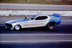 a blue and white race car driving down the road