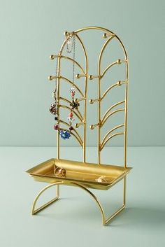 a gold jewelry holder with jewels on it's sides and a necklace hanging from the top