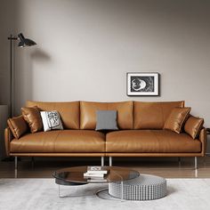 a brown leather couch sitting in a living room next to a coffee table and lamp