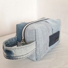 a denim bag with zippers on the front and side, sitting on a white surface