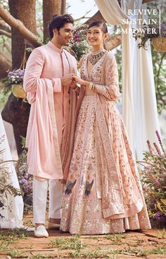 a man and woman standing next to each other in front of an arch with flowers