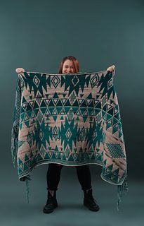 a woman holding up a green and white blanket