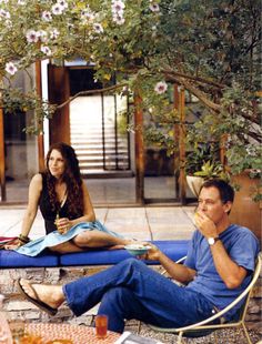 a man and woman sitting on lounge chairs outside