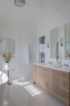 a large bathroom with two sinks, mirrors and bathtub in it's center