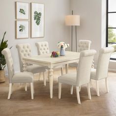 a white dining room table and chairs in front of a window