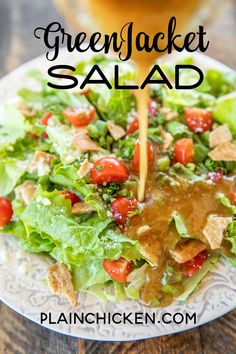 a salad with dressing being poured onto it on a white plate next to a glass of beer