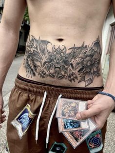 a man with tattoos on his stomach holding cards