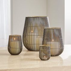 three decorative vases sitting on top of a table next to each other with candles in them