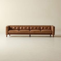 a brown leather couch sitting on top of a white floor next to a wooden frame