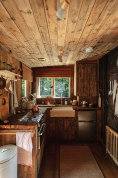 a kitchen with wooden walls and flooring next to a sink, stove top oven and dishwasher