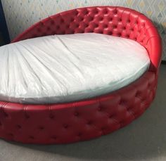 a red round bed with a white sheet on it's headboard and foot board