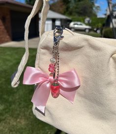 a bag with a pink bow hanging from it's front end and a chain attached to it