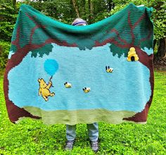 a person standing in the grass holding up a blanket with winnie the pooh on it