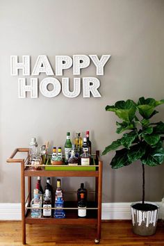 a bar cart with liquor bottles on it in front of a happy hour sign