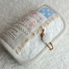 a small white purse sitting on top of a lace covered table cloth next to a hook