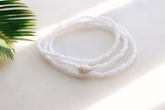 Matte Coconut white seed beads strung on stretch cord finished with a natural sea shell Bracelet can be wrapped around the wrist 3 times. Fits the average sized wrist (7 inches) The string total length is approximately 21 inches. Can also be worn as an anklet or a necklace. If you need a customized length or would like your bracelet to have more layers, please feel free to message me for a custom order! Handmade with love by Amanda 🐚 Surf wave bracelet can be found here: https://etsy.me/2DSXXfa White Hand-strung Bracelets For Beach, White Hand-strung Beaded Bracelets For Beach, White Hand-strung Beaded Bracelet For Beach, White Shell Beaded Bracelets For Summer, White Beaded Bracelets For Beach With Round Beads, White Beaded Bracelets For The Beach, White Strand Stretch Bracelet For The Beach, Summer White Shell Beaded Bracelets, White Shell Beaded Strand Bracelets