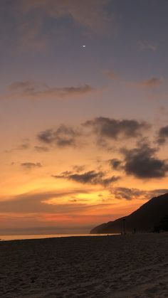 the sun is setting at the beach with people on it