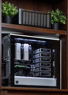 the inside of a computer case with plants and other things in it on top of a wooden shelf