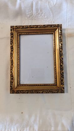 an old gold frame sitting on top of a white sheet