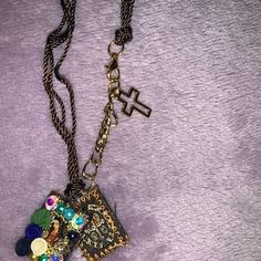 a necklace with a cross on it and beads hanging from the chain, sitting on top of a purple blanket